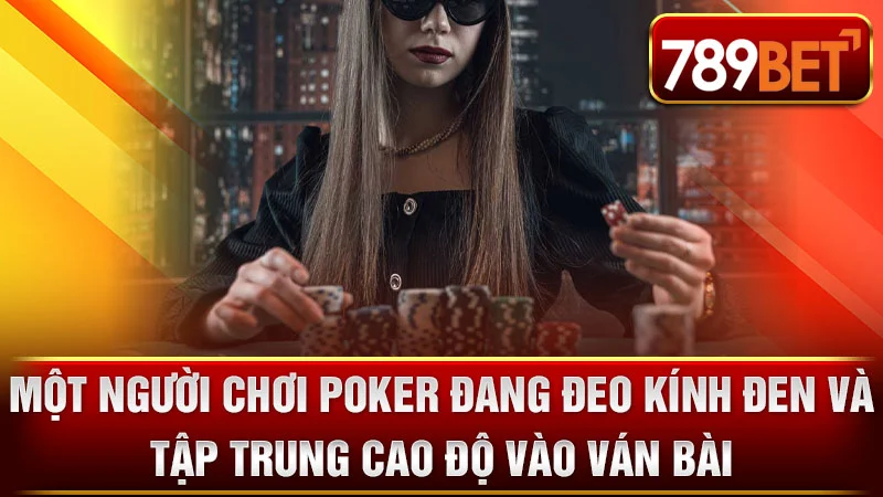 Một người chơi Poker đang đeo kính đen và tập trung cao độ vào ván bài.